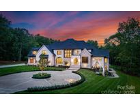 Stunning estate home with lush landscaping, circular driveway, and elegant stone and stucco exterior at 15037 June Washam Rd, Davidson, NC 28036