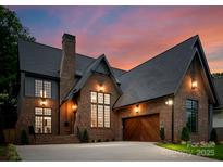 Stunning brick home featuring a large garage, multiple windows, black roof, and a professionally landscaped yard at 2921 Windsor Ave, Charlotte, NC 28209