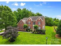 Beautiful two-story brick home featuring a well-manicured lawn and mature trees at 3213 Strawberry Rd, Matthews, NC 28104