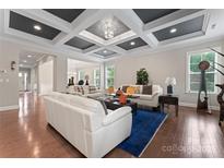 Bright living room with hardwood floors, white sofas, and coffered ceiling with recessed lighting at 4008 Pinot Way, Fort Mill, SC 29707