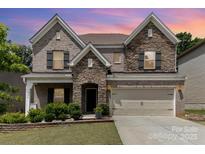 Beautiful two-story home with a stone and brick facade, complemented by a manicured lawn and attached two-car garage at 5098 Burnwald Ct, Fort Mill, SC 29715