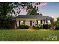 Charming home featuring a well-manicured lawn and front porch, set against a lovely sunset sky at 1512 Anthony Dr, Gastonia, NC 28052