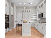 Bright kitchen features white cabinets, wooden floors, an island with seating and pendant lighting at 4015 Randolph Rd, Charlotte, NC 28211