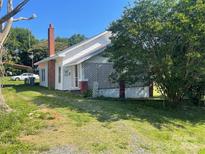 Charming home features a red brick chimney and a lattice-enclosed porch, nestled on a lush lawn at 408 Moose St, Albemarle, NC 28001