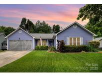 Charming one-story home with manicured lawn, beautiful landscaping and periwinkle blue siding at 5711 Lambrook Ct, Charlotte, NC 28269