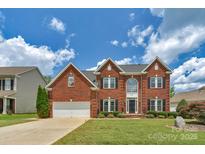 Charming two-story brick home with a well-manicured lawn and beautiful landscaping under a cloudy sky at 7800 Conifer Cir, Indian Trail, NC 28079