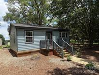 Charming blue home with a metal roof, brick foundation and stairs, surrounded by mature trees and a mulched yard at 9280 W Nc 152 Hwy, Mooresville, NC 28115