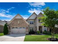 Charming two-story home featuring a blend of brick and stone, a well-manicured lawn, and a two-car garage at 11313 Limehurst Pl, Charlotte, NC 28278