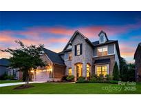 Striking exterior elevation featuring a stone facade, manicured lawn, and a dramatic sunset backdrop at 11313 Limehurst Pl, Charlotte, NC 28278