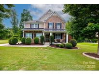 Charming two-story home featuring a manicured lawn and inviting front porch with stone and siding accents at 2405 Emma Grace Ln, Rock Hill, SC 29732