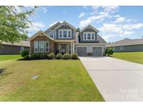 Charming two-story home with stone accents, a well-manicured lawn, and a three-car garage at 2606 Cheverny Pl, Concord, NC 28027