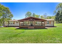 Charming ranch home with a large covered front porch and expansive yard on a sunny day at 2942 Denwood Dr, Claremont, NC 28610