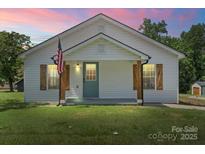 Charming single-story home with a well-manicured lawn, front porch, American flag, and rustic wooden shutters at 321 E Taylor St, Landis, NC 28088