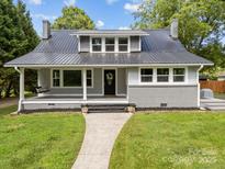 Charming home featuring a sleek metal roof, inviting front porch with swing, and well-manicured lawn at 1025 Old Us 80 Hwy, Gold Hill, NC 28071
