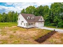 A charming white two-story home with a brown roof, attached garage, and a well-manicured lawn at 1471 Marshbrooke Ln, Catawba, NC 28609