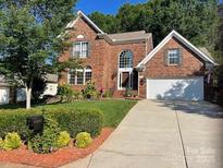 Charming two-story brick home with a well-manicured lawn, inviting curb appeal, and an attached two car garage at 15811 Burlingame Dr, Huntersville, NC 28078