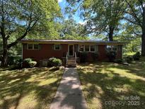 Charming brick ranch home with mature trees and a well-manicured lawn in a serene setting at 211 S Slack St, Albemarle, NC 28001