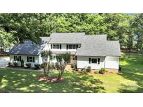 Charming two-story home with white siding, a gray roof, a well-manicured lawn, and mature trees at 316 Wade Hampton Dr, Matthews, NC 28104