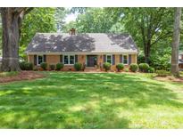 Charming brick home with a well-maintained lawn, lush landscaping, and mature trees at 629 Wingrave Dr, Charlotte, NC 28270