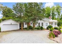 Charming white home with a gravel driveway, mature trees, and a two-car garage offering a blend of comfort and curb appeal at 805 S Main St, Mount Holly, NC 28120