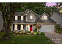 Charming two-story home with a red door, landscaped yard, and inviting front porch at 8700 Fox Tail Ln, Huntersville, NC 28078