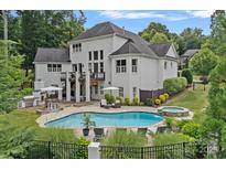 Expansive backyard with a large pool, spa, outdoor kitchen, and seating area perfect for entertaining and relaxation at 109 Walking Horse Trl, Davidson, NC 28036