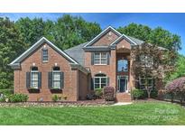 Stunning brick home featuring lush landscaping, a manicured lawn, and charming architectural details at 12644 Lahinch Ct, Charlotte, NC 28277
