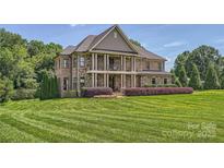 Stunning stone home with a manicured lawn and covered front porch with columns, showcasing elegance at 14041 Mccord Rd, Huntersville, NC 28078