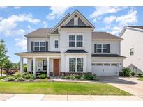 Charming two-story home boasts a manicured lawn, inviting porch, and a two-car garage at 15103 Keyes Meadow Way, Huntersville, NC 28078