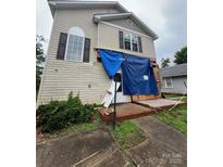 Damaged two-story home featuring a front porch, siding, and windows covered with a blue tarp at 2012 Ashley Rd, Charlotte, NC 28208