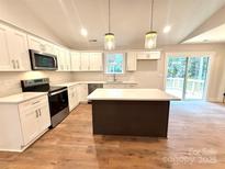 Bright kitchen features white cabinets, stainless appliances, quartz countertops, and center island with wood laminate flooring at 2330 Neill Rd, Lancaster, SC 29720