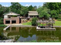 Beautiful waterfront home featuring a dock and multi-car garage, surrounded by lush landscaping and serene water views at 24756 Strand Dr, Albemarle, NC 28001