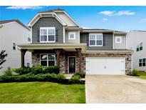 Charming two-story home featuring a stone facade, two-car garage, and well-manicured lawn at 334 Kennerly Center Dr, Mooresville, NC 28115