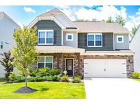 Charming two-story home featuring stone accents, a two-car garage, and a well-maintained lawn with mature tree at 334 Kennerly Center Dr, Mooresville, NC 28115