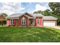 Charming brick home featuring red shutters, a well-manicured lawn, and a two-car garage at 4320 Atkinson Way, Monroe, NC 28110