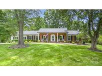 Charming brick home with inviting front porch, rocking chairs, and beautifully landscaped front yard at 441 Crestside Se Dr, Concord, NC 28025