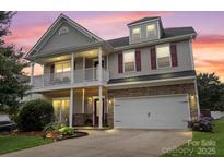 Inviting two-story home featuring a charming front porch, stone accents, and a well-manicured lawn at 5111 Elementary View Dr, Charlotte, NC 28269