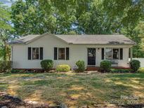 Charming one-story home featuring a well-maintained lawn, black shutters, and inviting front porch bench at 713 Springfield Nw Dr, Concord, NC 28027