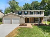 Charming two-story home featuring a two-car garage, neutral siding, and lush landscaping at 7134 Rollingridge Dr, Charlotte, NC 28211