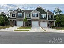 Three-unit townhouse with brick and vinyl siding, individual garages, and manicured lawns at 8060 Scarlet Maple Ln, Tega Cay, SC 29708