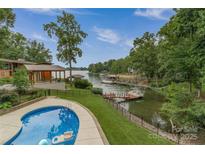 Inviting backyard with a swimming pool and covered patio overlooking the serene waterfront at 8593 Bailey Dr, Terrell, NC 28682