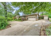 Traditional tan brick home featuring an attached two-car garage and long concrete driveway at 203 Ewing Dr, Belmont, NC 28012