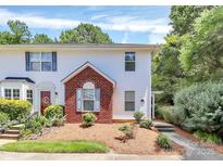 Charming two-story townhome featuring white siding, a brick facade, and a well-manicured front yard with lush landscaping at 4263 Melrose Club Dr, Matthews, NC 28105