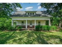Charming single-story home featuring a covered front porch with white pillars, surrounded by mature trees and a lush green lawn at 4612 Rehobeth Rd, Waxhaw, NC 28173