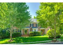 Traditional brick home featuring a manicured lawn and mature trees enhancing the curb appeal at 5008 Woodview Ln, Weddington, NC 28104