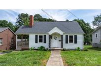 Charming white home featuring a brick chimney, black shutters, and a covered porch at 626 1St Se Ave, Hickory, NC 28602