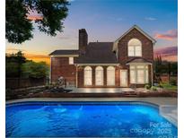 Inviting backyard with a refreshing pool, brick home, and outdoor space, perfect for relaxation and entertainment at 7213 Baniff Cir, Charlotte, NC 28277