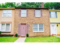 Charming brick townhome with muted pink shutters, well-manicured lawn, and inviting front entrance at 7526 Holly Grove Ct, Charlotte, NC 28227