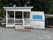 Charming exterior view featuring a white picket fence, covered porch, and a gravel yard at 109 Pine St, New London, NC 28127