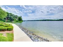 Picturesque waterfront view with a paved path, lush greenery, and stunning lake views, perfect for serene living at 14053 Queens Harbor Rd, Charlotte, NC 28278